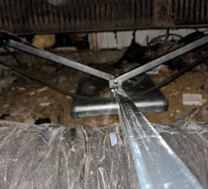 A metal pipe is securely fastened to the underside of a bed frame, providing structural support.